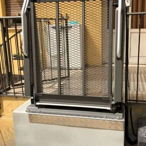 Low-rise wheelchair platform lift bridging entry steps at a residential porch Low-rise wheelchair platform lift bridging entry steps at a residential porch
