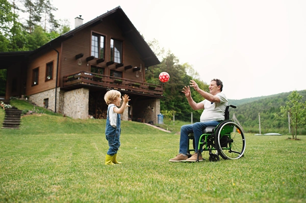 Child standing beside senior man in wheelchair
